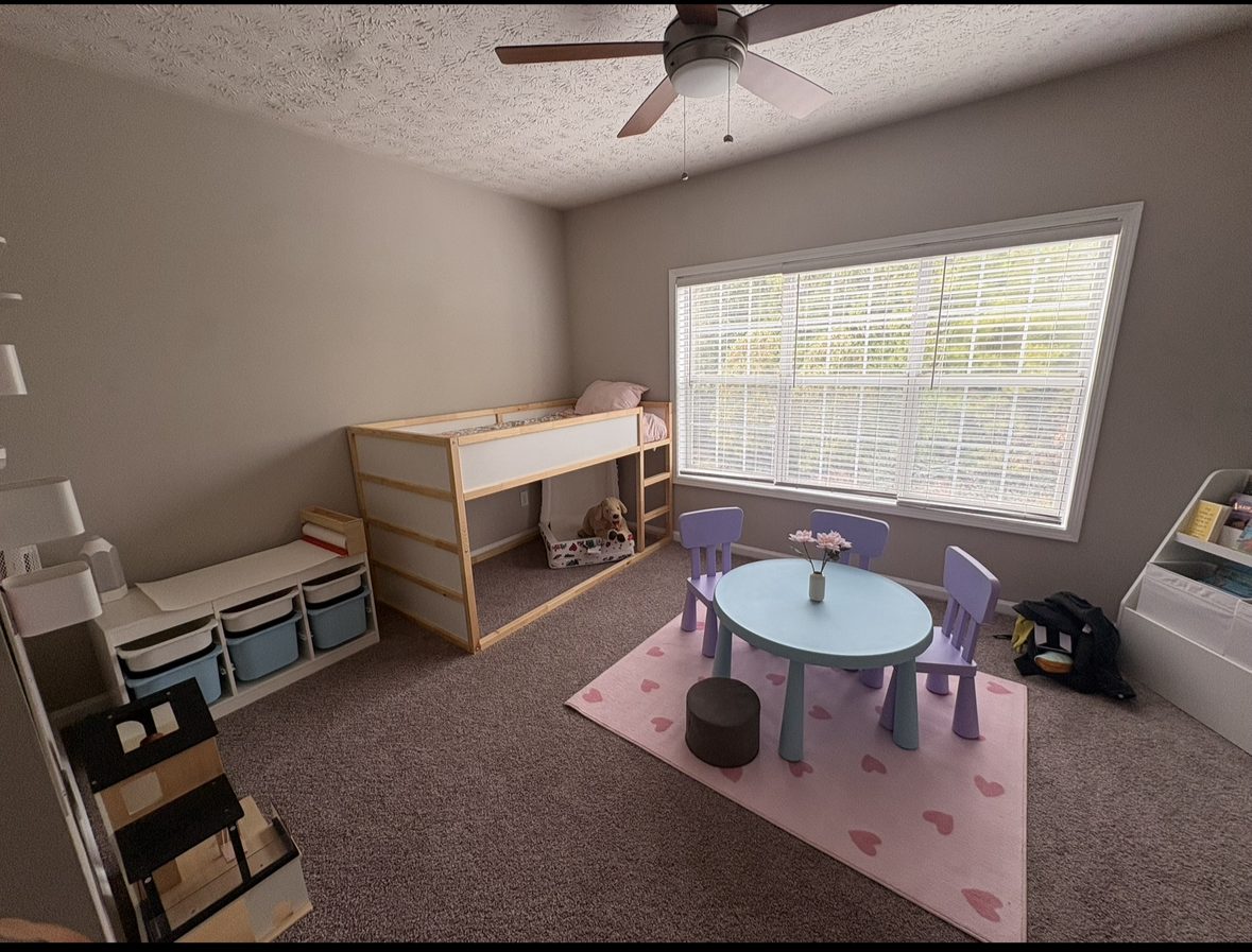 Organized kids' playroom with labeled storage bins, a play table, and a reading nook